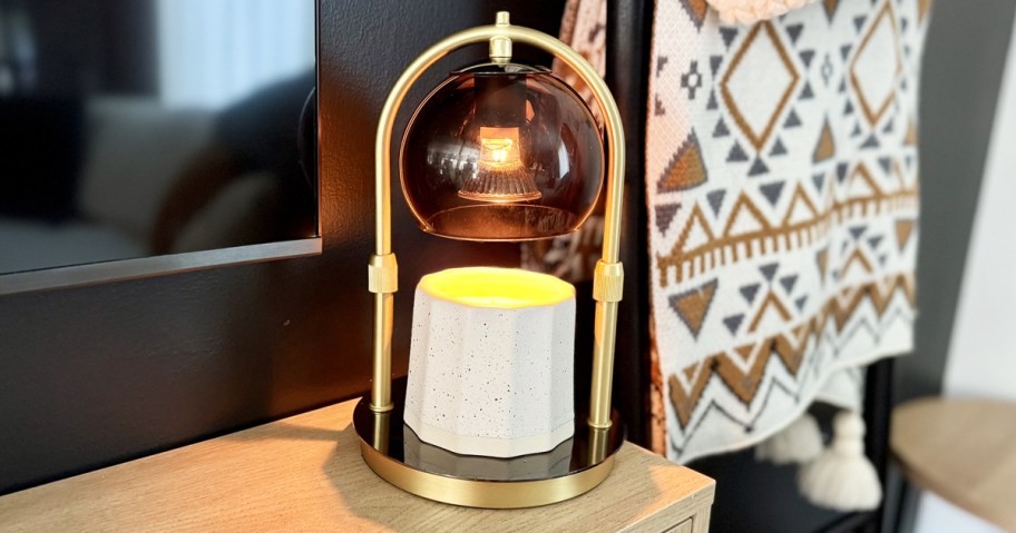 white jar candle under an arched candle warmer lamp