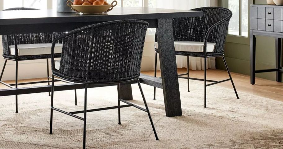 A dark colored dining room table with dark colored chairs