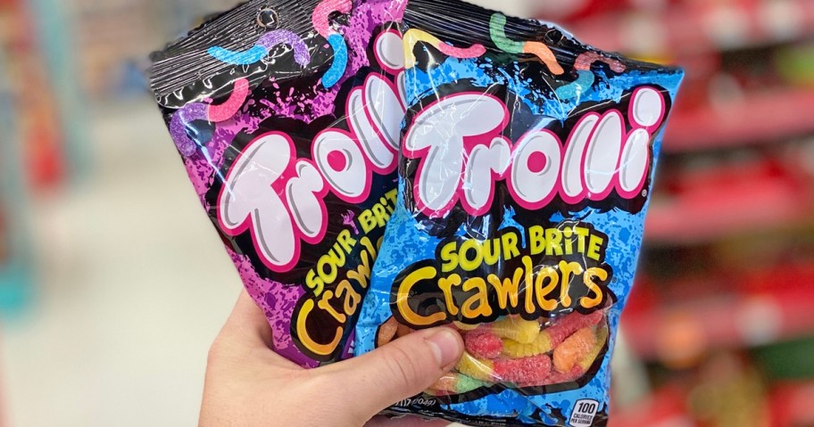 hand holding up two bags of Trolli Gummy Worms in store