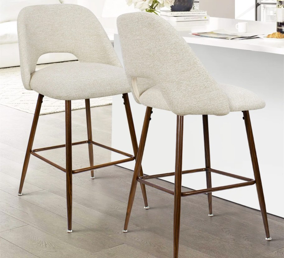 two white upholstered bar stools with wood legs