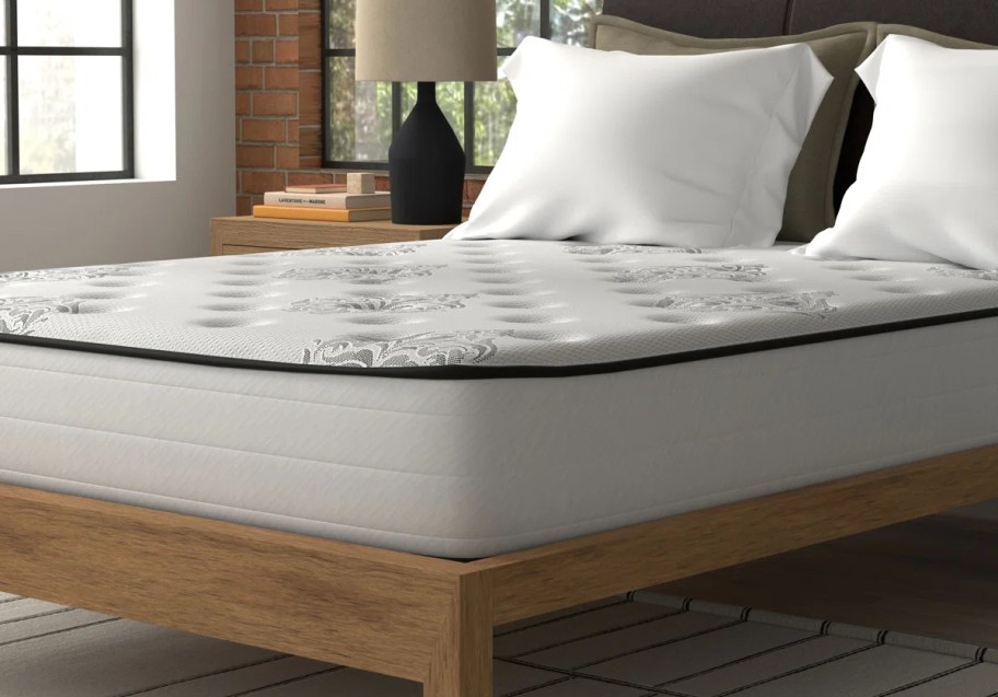 Corner of white mattress with a no sheets and pillows on top