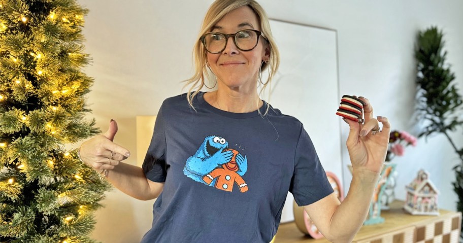woman pointing to her cookie monster shirt while holding stack of cookies