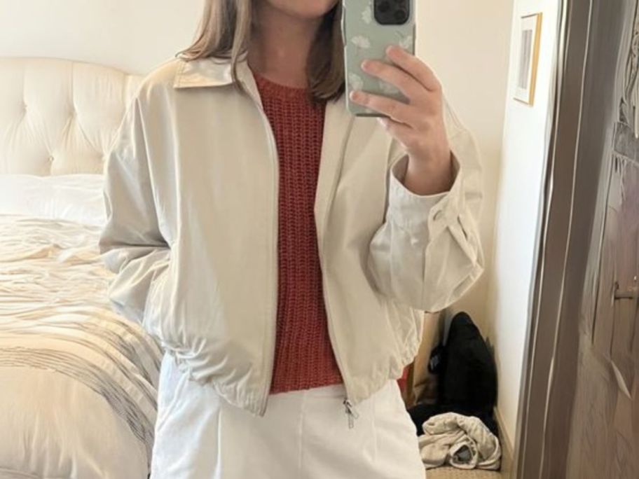 woman wearing cream colored abercrombie jacket and taking selfie