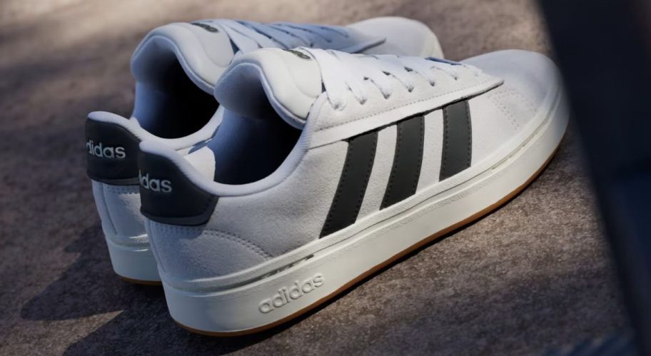 A pair of white sneakers with black stripes, sitting on top of a road