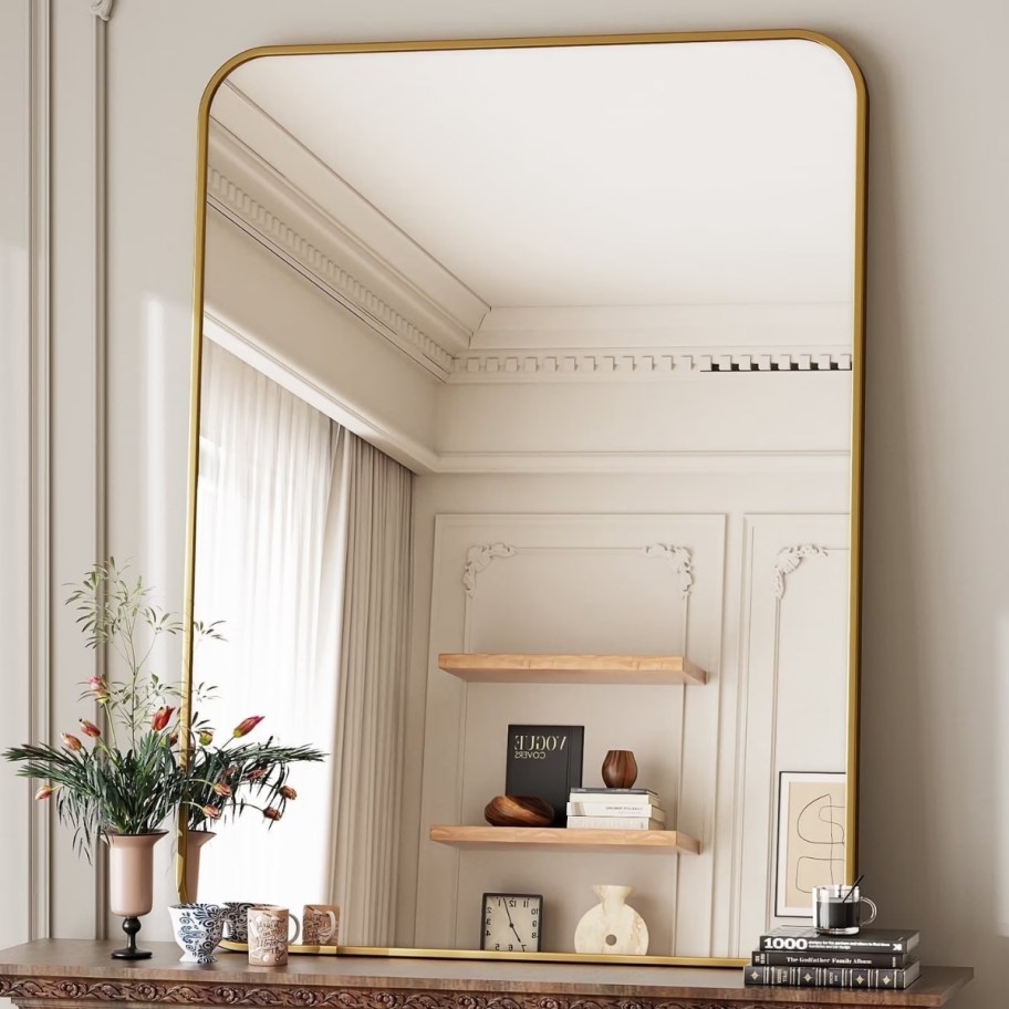 a gold framed rectangular rounded corner mirror over a mantle