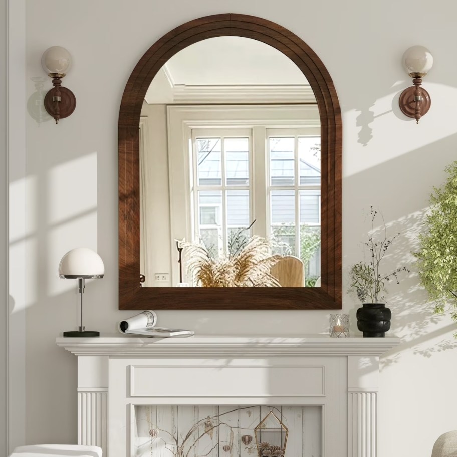 an arched wooden frame mirror over a mantle
