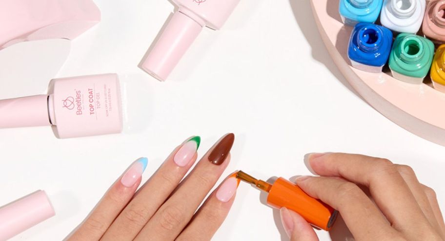 beetles nail polish being used on different nails with polish near them