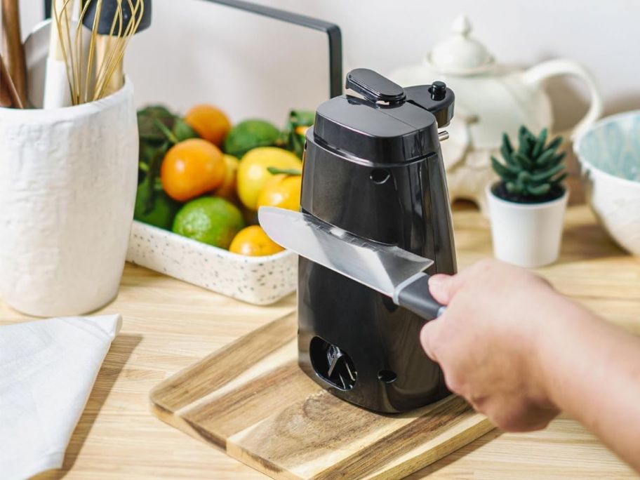 hand holding knife in knife sharpener feature of electric can opener