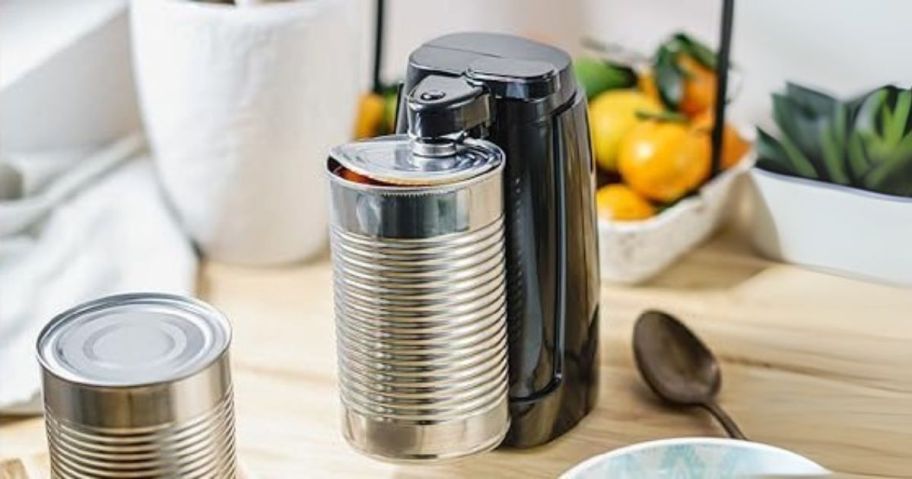 black electric can opener on counter and opening a can
