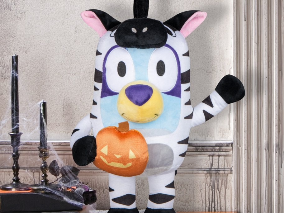 bluey porch greeter in zebra costume holding a plush pumpkin