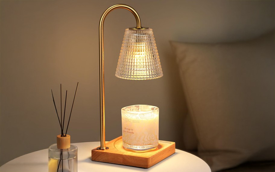 candle warmer lamp on a table sitting next to a bed