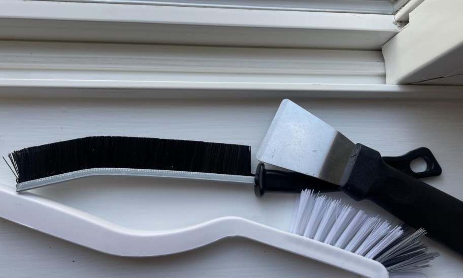 two assorted crevice brushes with scraper too on a window sill