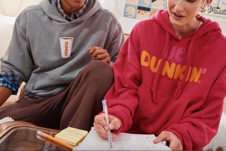 man in grey hoodie with coffee girl in red hoodie with dunkin letters