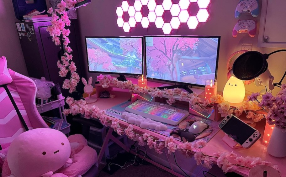 pink gamer setup with two monitor and pink lights on walls