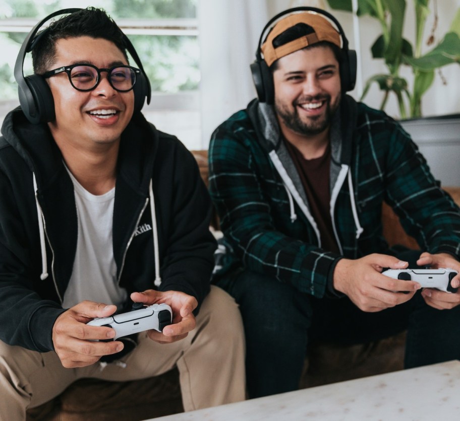 two men wearing headphones playing video game on couch