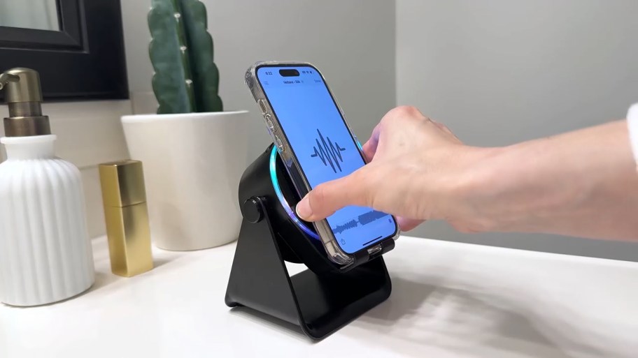 person putting a phone on an induction speaker