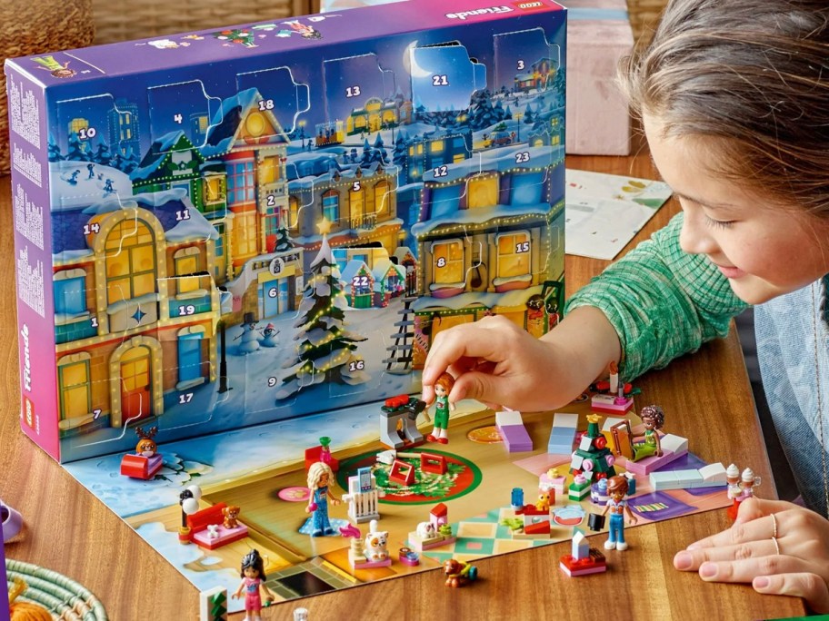 girl playing with lego advent calendar pieces in front of box