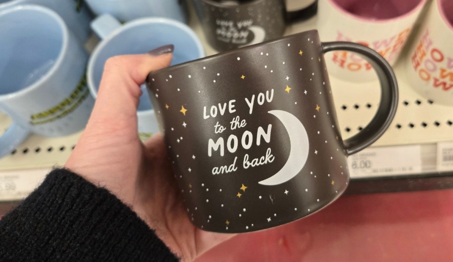 a womans hand holding a coffee mug