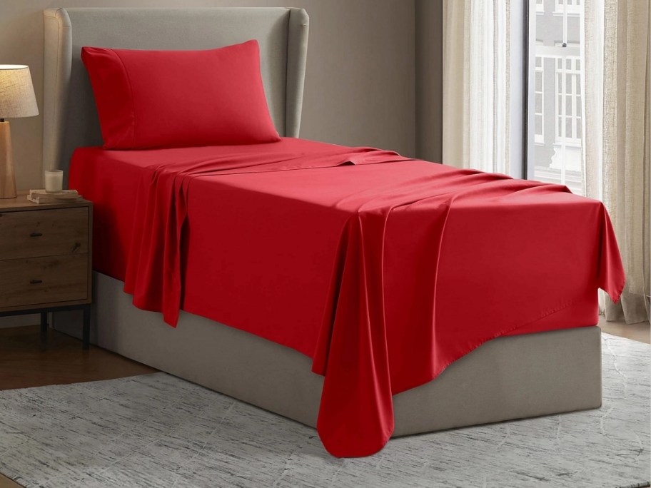 a twin bed with red sheet set