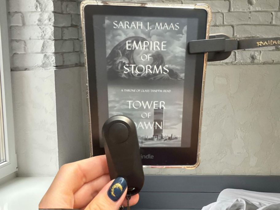 hand holding ereader remote control in front of kindle