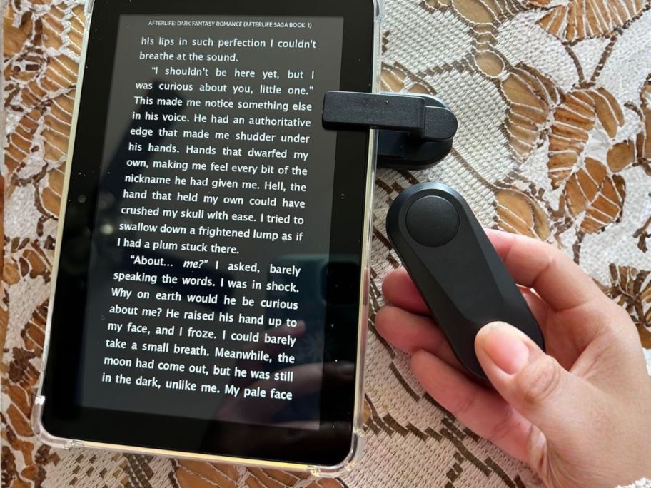 hand holding ereader remote control next to kindle