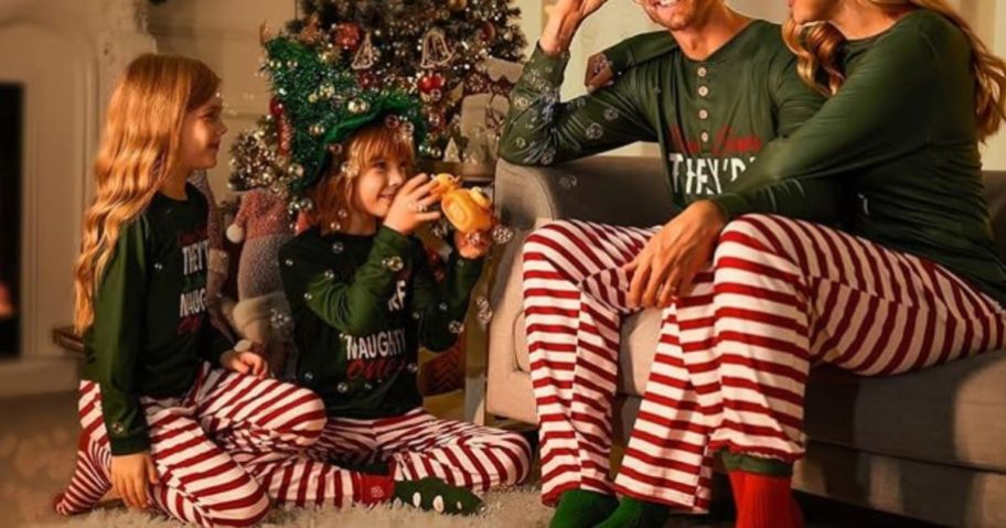 family sitting in front of a christmas tree wearing matching pajamas