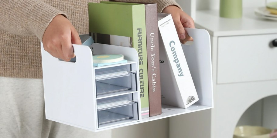 person holding white drawer holder with books