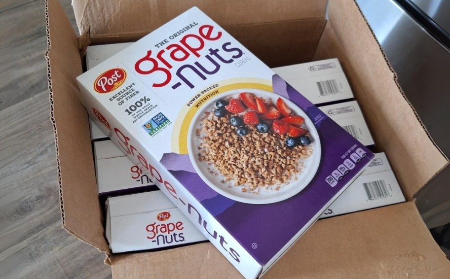 a box of grape nuts cereal on top of a cardboard box filled with cereal boxes