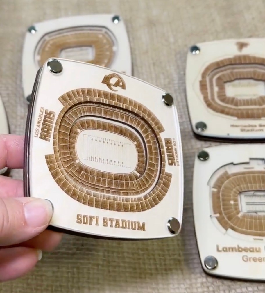 hand holding an engraved stadium coaster 