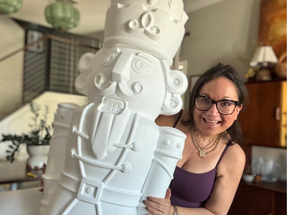 woman holding a large plastic Christmas Nutcracker figure