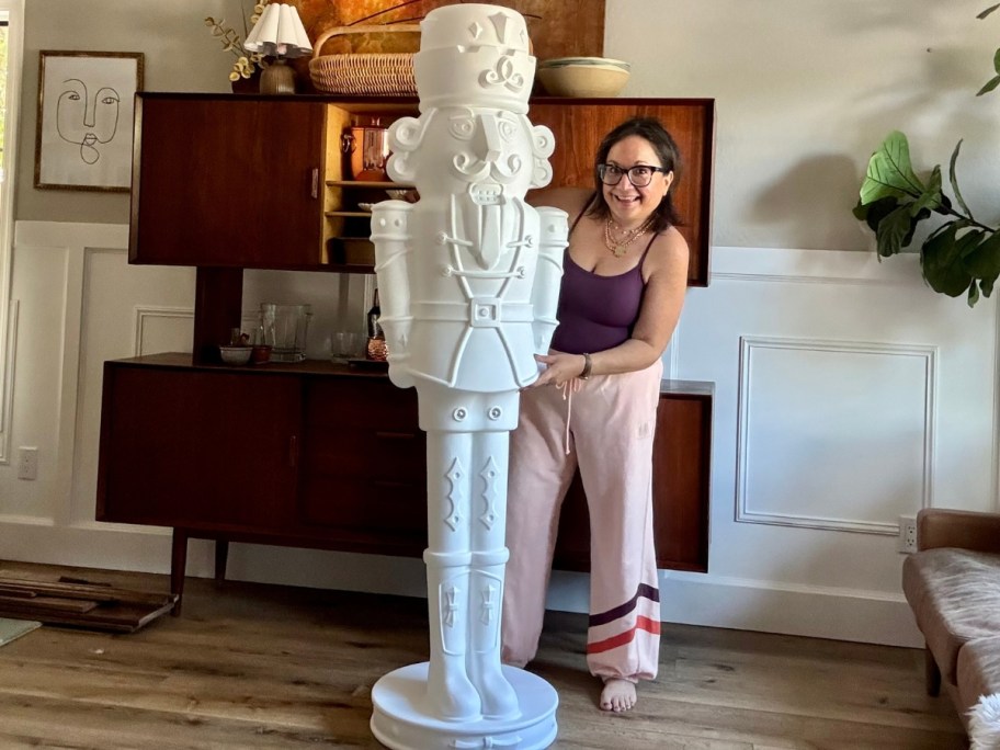woman standing next to a large white Christmas Nutcracker blow mold