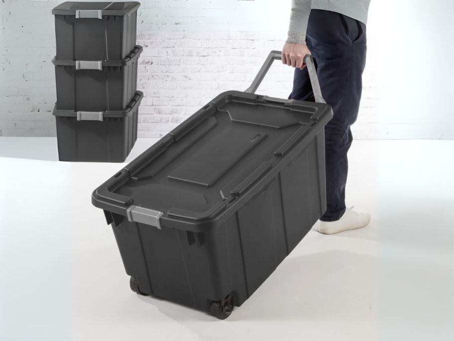 person holding gray Sterilite 40-Gallon Wheeled Industrial Tote