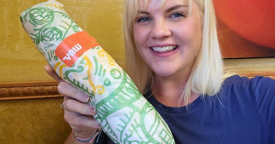 A blond woman holding a Subway sandwich