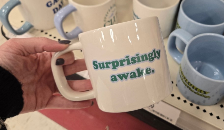 a womans hand holding a coffee mug