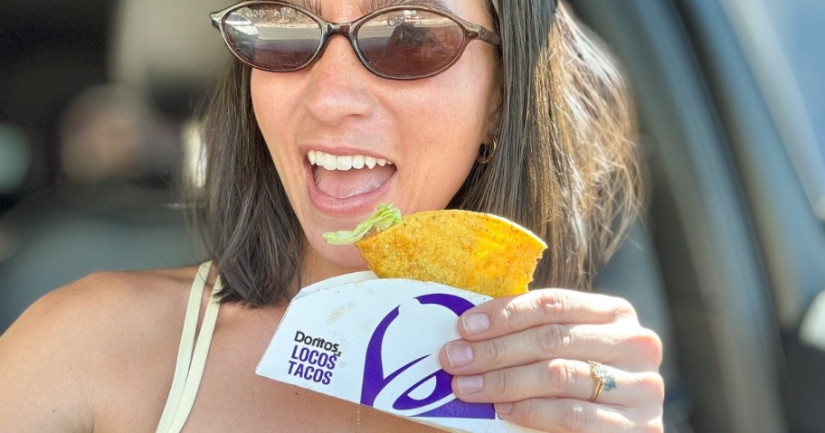 woman holding a taco and smiling at the camera