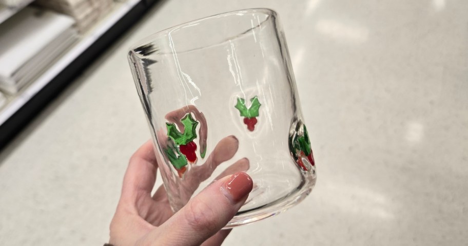 hand holding a juice glass with holly berries