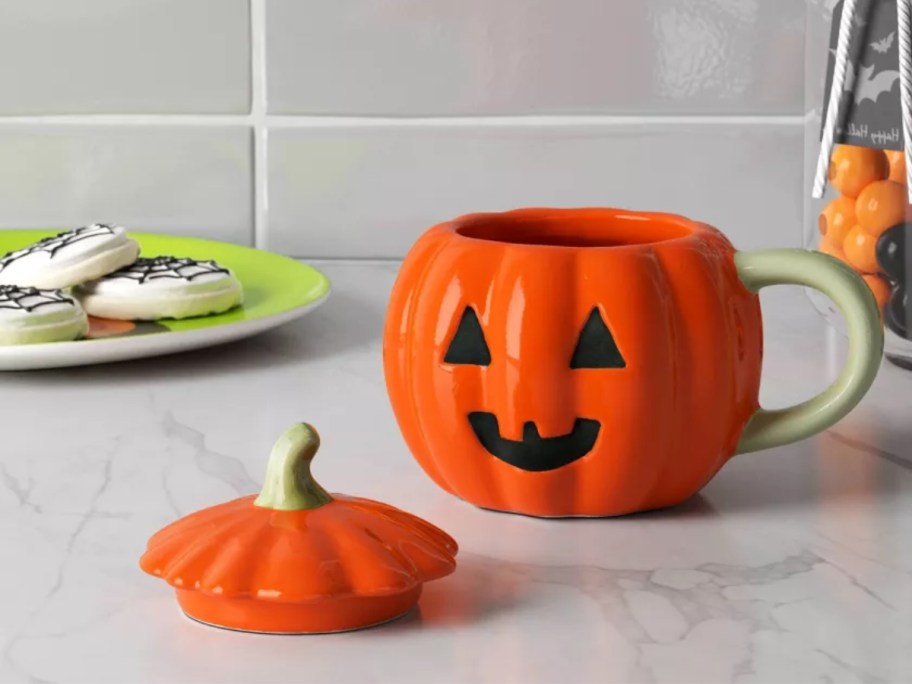 a jack-o-lantern coffee mug with a lid on a kitchen counter