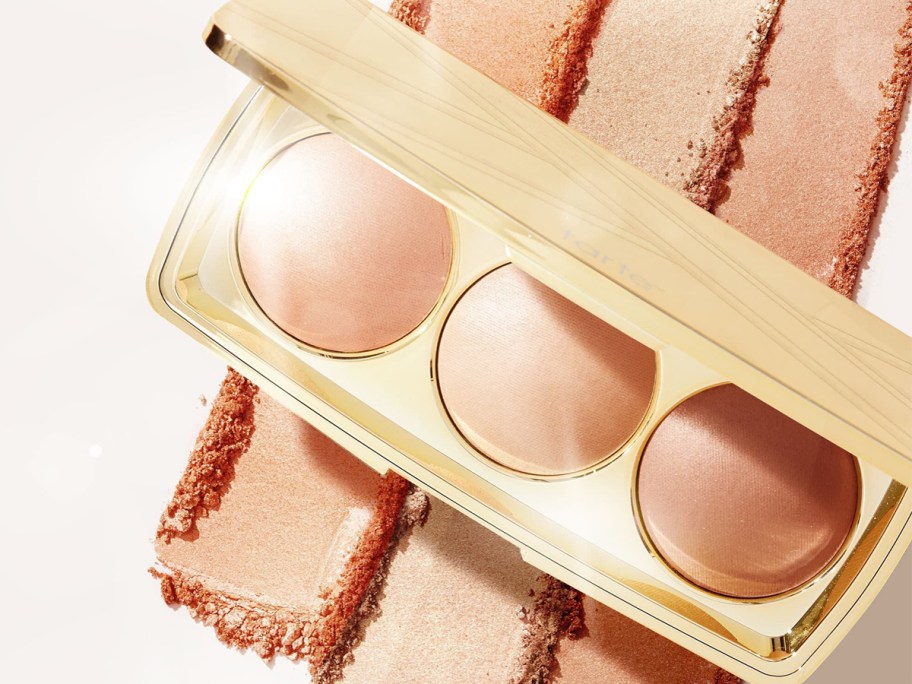 opened gold highlighter compact with swatches behind it