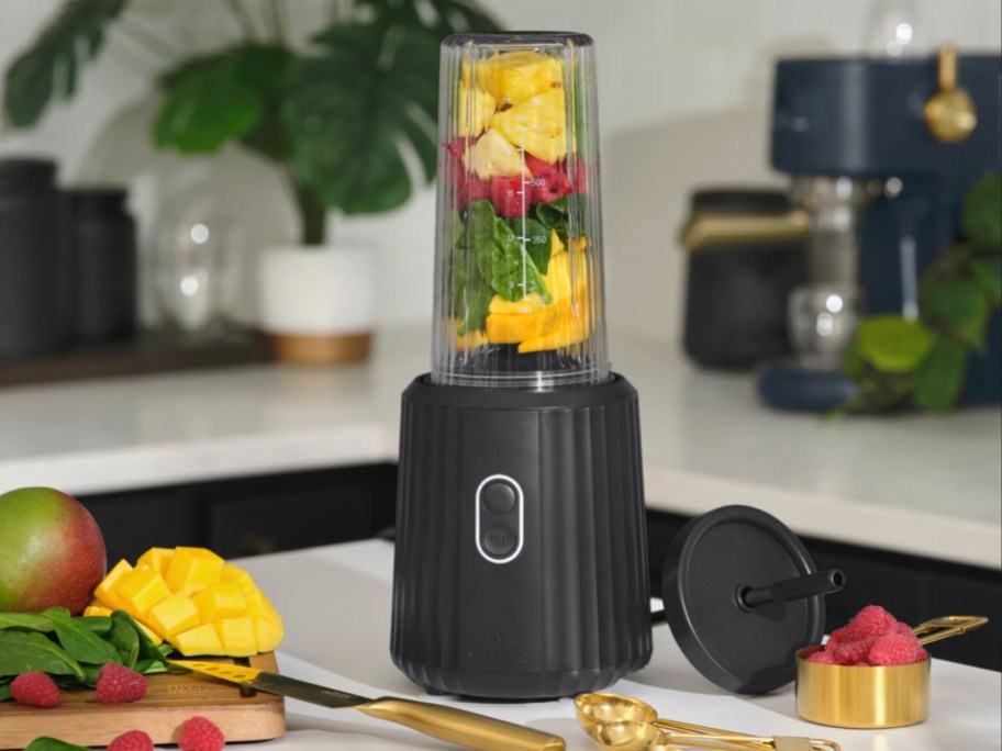 black ribbed blender with single serve cup with fruits in it