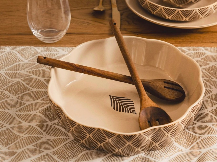 a serving bowl with a wooden fork and spoon on a table