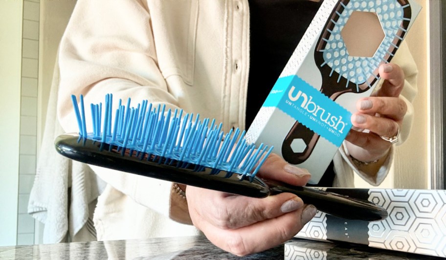 woman holding out a blue and black unbrush and box
