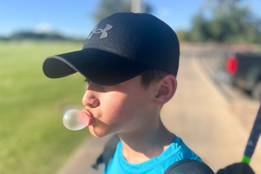 boy blowing bubble gum outside in black hat