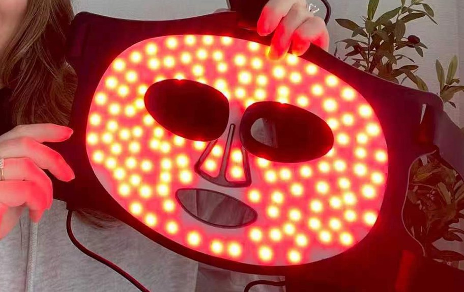 person holding red light therapy mask