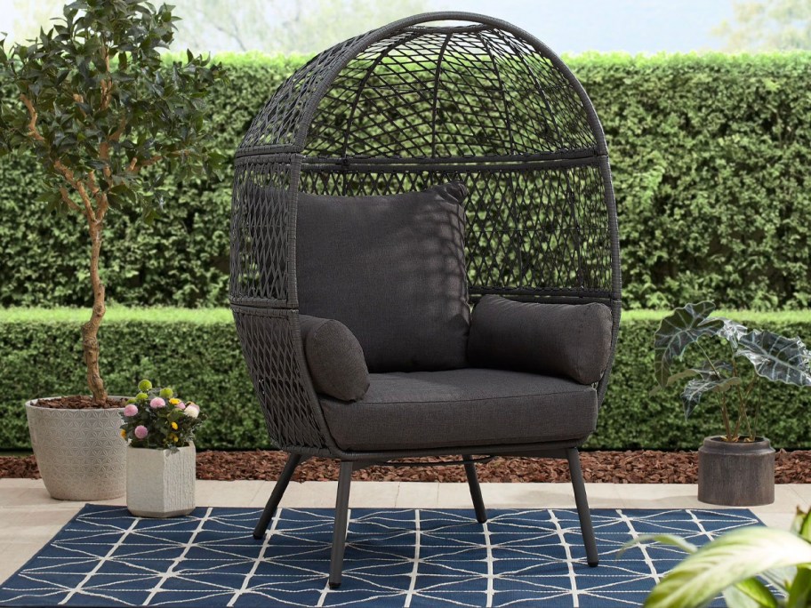 gray egg chair on patio with blue rug