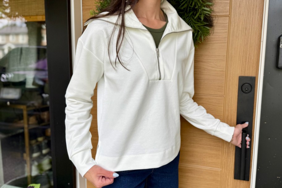 woman grabbing door handle in white collared zipper pullover sweatshirt