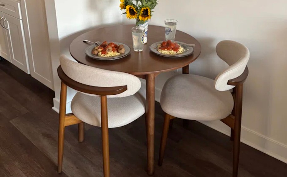 Small dining room table with two chairs and pasta and meatballs on table 