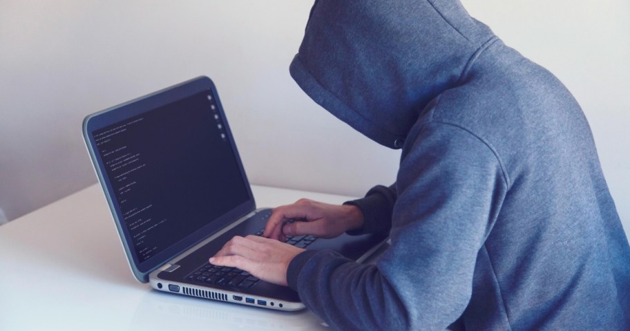 Person typing on laptop with hoodie on