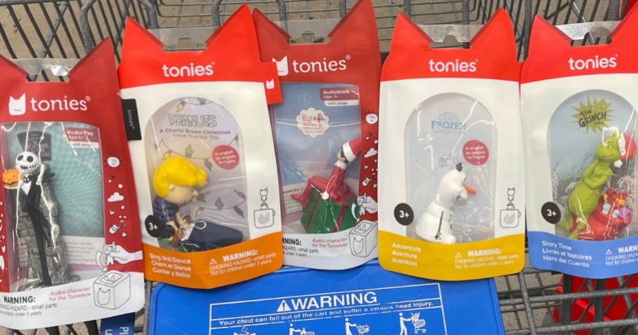 a Walmart shopping cart with various Christmas Tonies figures in the packaging they come in
