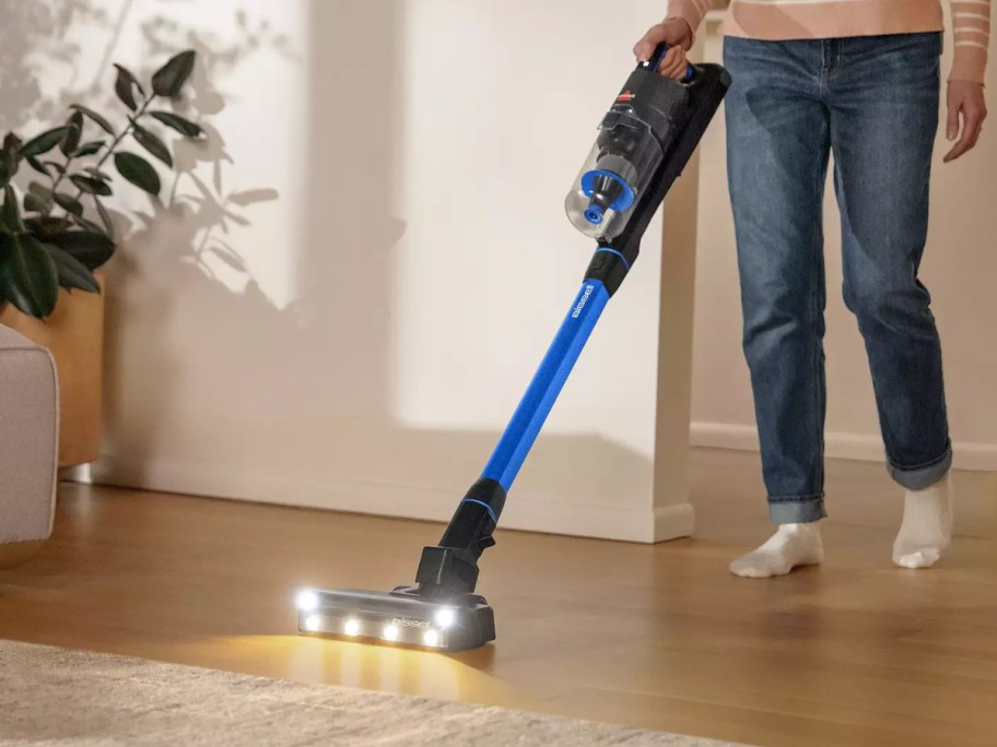 woman using a cordless stick vacuum