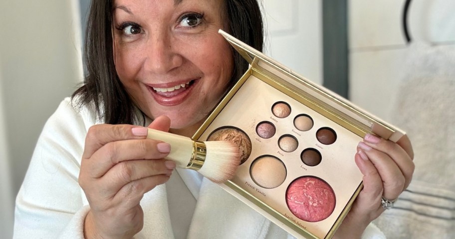 woman putting makeup on a brush from a palette
